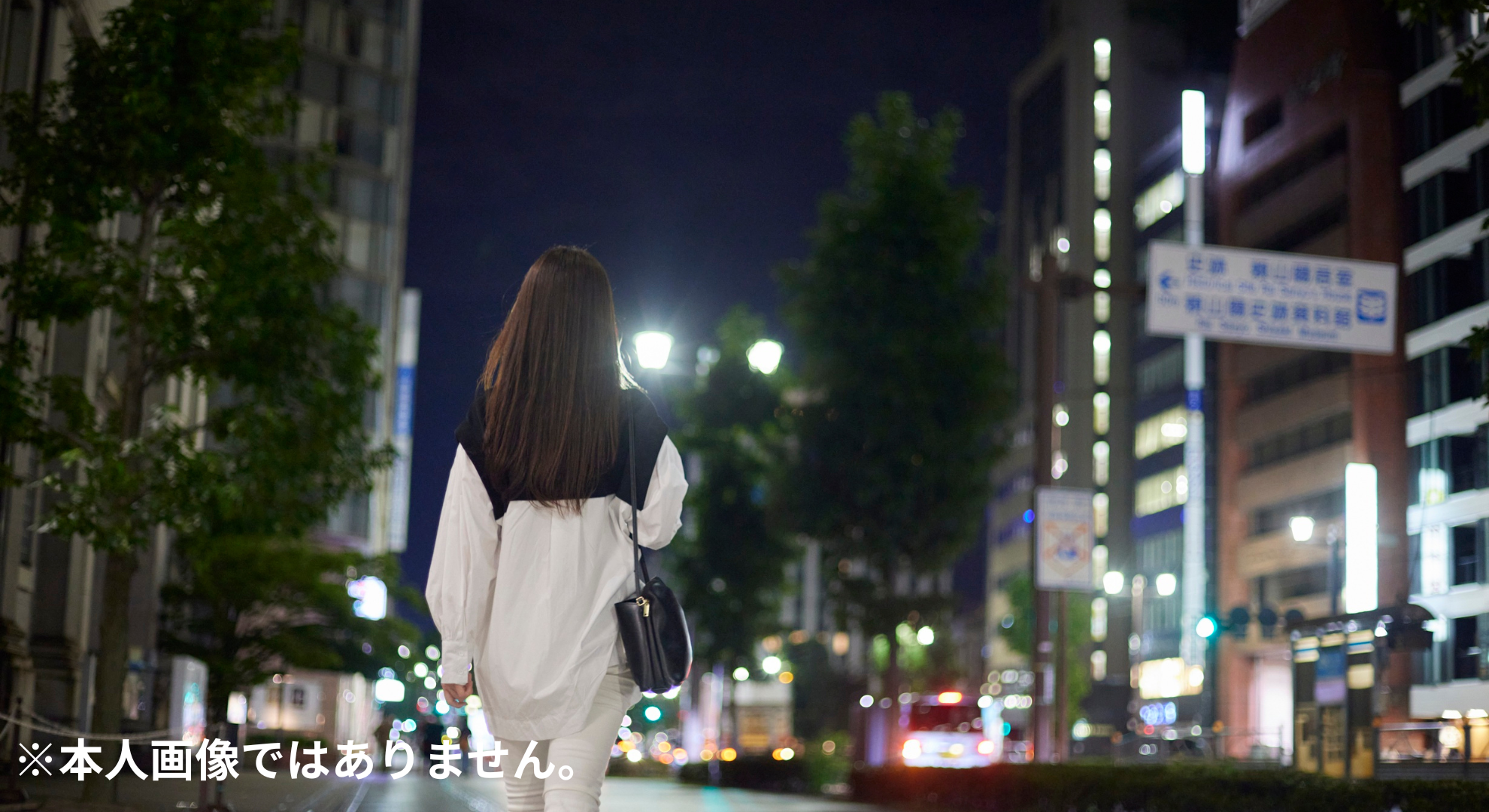 日本人の20代女性の後ろ姿。夜のネオンが光る都会の通りを歩いている。少しレトロな90年代風の雰囲気で、爽やかだけど芯の強さも感じるイメージ。蓮舫さん本人ではありません。