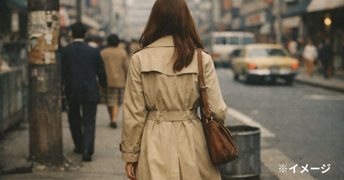1970年代前半の都会の歩道、トレンチコート風の“架空の若い女性”の後ろ姿